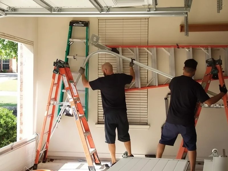 Two workers assessing a raised sectional garage door