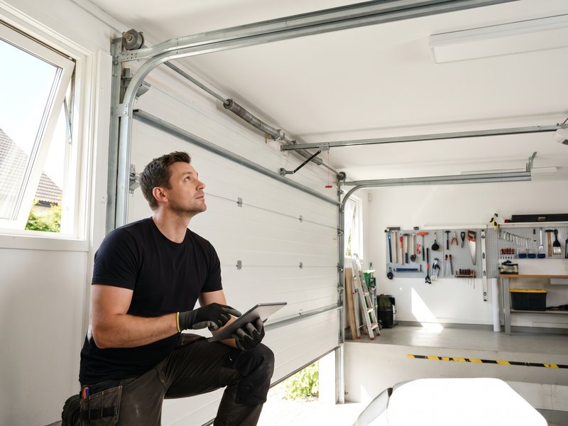 Technician inspecting a ceiling-mounted garage door opener