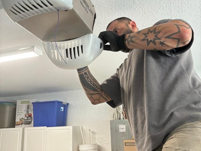 Worker checking a ceiling-mounted garage door opener