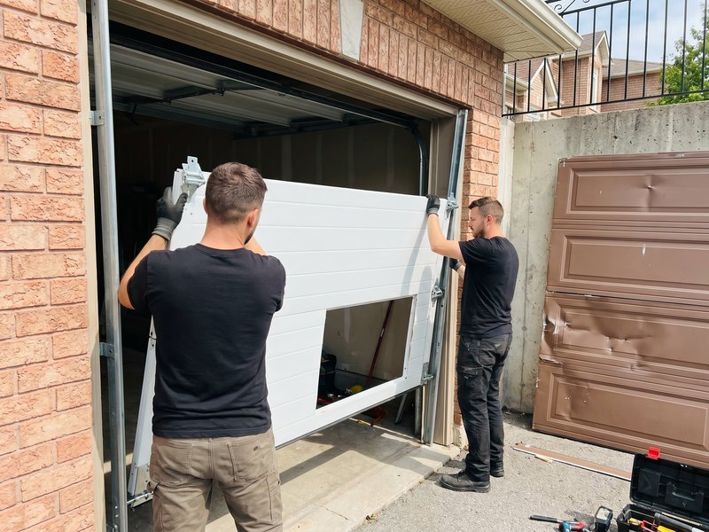 Two workers holding a white replacement door section