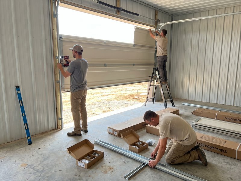 Two installers fitting sectional panels at a garage opening